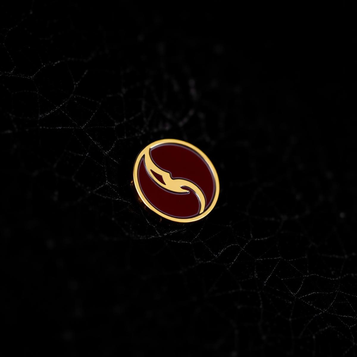 Gold and burgundy enamel pin on dark leather